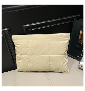 Detail einer gesteppten beigen Laptoptasche mit gepolstertem Rautenmuster auf Leder