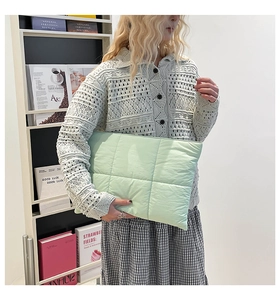 Makroaufnahme einer minzgrünen gesteppten Nylon-Handtasche, gehalten von einem Modell