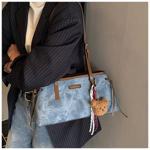 Detail van blauwe shopper met bruine leren bies en een schattige teddybeer hanger