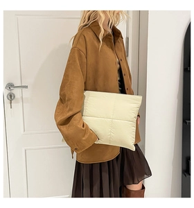 Detailansicht einer cremefarbenen Stepptasche kombiniert mit einer braunen Wildlederjacke