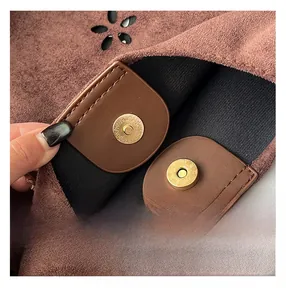 Detailed view of the magnetic closure on a brown suede tote bag with gold-tone hardware