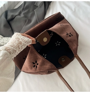 Detail view of large brown faux suede tote with laser-cut floral patterns and magnetic clasp