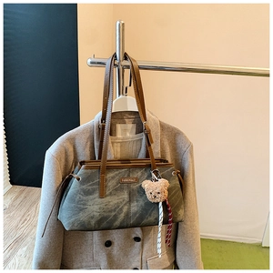 Detail van een vintage grijsblauwe canvas tas met lederen riem en schattige beer hanger