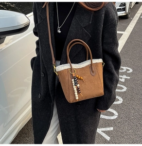 Détail d'un sac seau en daim marron avec garniture en polaire blanche et pendentif
