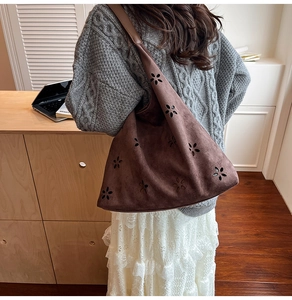 Close-up of brown faux suede tote bag with laser-cut floral patterns on a model