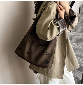 Detail view of large dark brown suede tote bag featuring laser-cut floral patterns