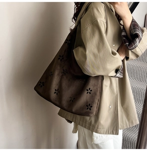 Detail of dark brown suede tote featuring laser-cut floral patterns and large capacity