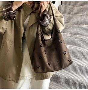 Detail of laser-cut floral pattern on dark brown faux suede tote bag with matte finish
