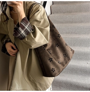 Detailed close-up of dark brown suede tote bag with intricate laser-cut floral patterns