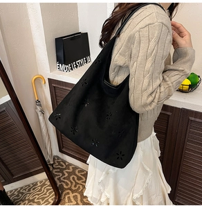 Detail view of black faux suede tote bag featuring intricate laser-cut floral patterns
