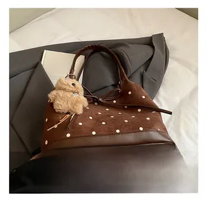 Detailed view of polka dot tote bag with leather bow and plush bear charm on soft fabric
