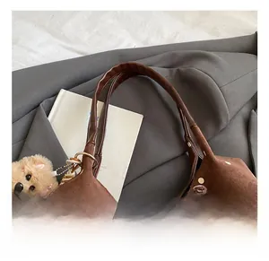 Close-up of brown suede polka dot tote bag with leather handle and cute bear charm
