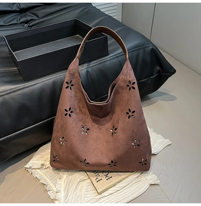 Detail of laser-cut floral pattern and suede texture on vintage brown tote bag