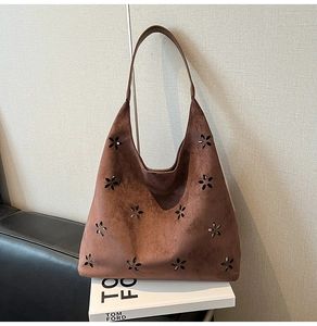 Close-up of brown suede tote bag featuring intricate floral cut-outs and soft texture