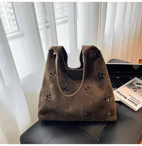 Detailed close-up of coffee brown suede tote bag featuring artistic floral cut-outs