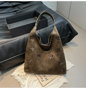 Detail of laser-cut floral pattern on a vintage dark brown suede tote bag