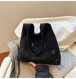 Detail of laser-cut floral pattern on a black suede tote bag for daily commute