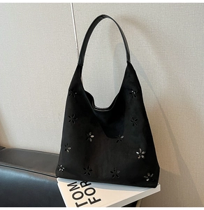 Detailed close-up of floral perforated suede tote bag with black glossy leather handles