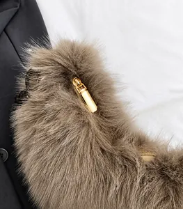 Close-up of golden metal zipper puller on a fluffy brown plush shoulder bag for women