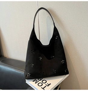 Detail of laser-cut floral patterns on black faux suede oversized hobo tote bag