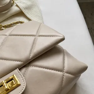 Dettaglio della trama in pelle beige trapuntata e catena in metallo dorato sulla borsa