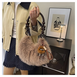 Detalle de bolso de piel sintética con asa de cuentas de madera y colgante de peluche