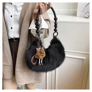 Detalle de bolso hobo de piel sintética negra con asa de cuentas de madera y dije de oso