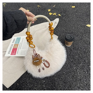 Detalle de bolso de felpa crema con asa de cuentas y colgante de muñeco de peluche
