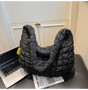 Détail du sac hobo matelassé noir montrant l'étiquette Fashion jaune et la texture nylon