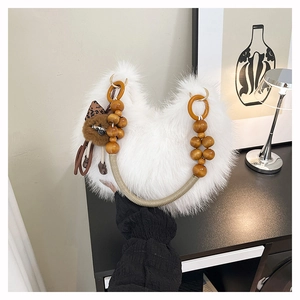 Detalle de bolso blanco de pelo sintético con asa de cuentas de madera y colgante suave
