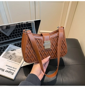 Close-up of brown quilted leather handbag with silver lock and fine stitching details