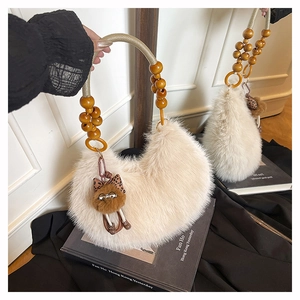Detalle del bolso beige de felpa con asa de cuentas de madera y colgante de gato