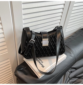 Detail showing woven texture and silver square metal clasp on black leather underarm bag