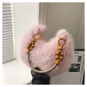 Detalle de bolso rosa de piel sintética con cuentas de madera y aros dorados