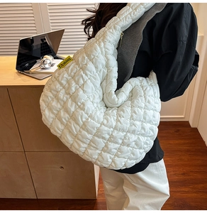 Détail du sac matelassé blanc avec fermeture éclair dorée et étiquette fashion