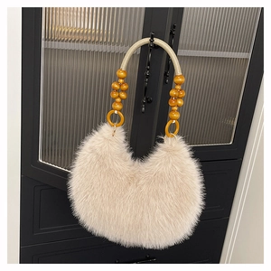Detalle de bolso de peluche con cuentas de madera y asa trenzada en puerta de vidrio