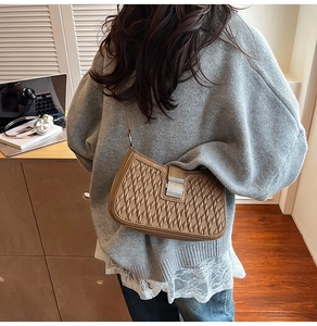 Detailed view of brown woven shoulder bag with square metal buckle and leather strap