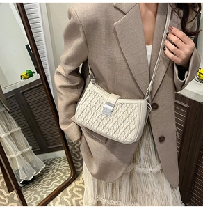 Close-up of cream woven faux leather crossbody bag with silver buckle and crossbody strap