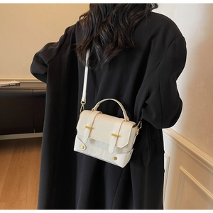 Detailweergave van de stijlvolle roomwitte mini crossbodytas gedragen door een model binnen