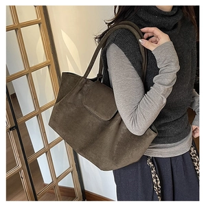 Vista lateral de un bolso tote grande de ante marrón oscuro llevado por una modelo
