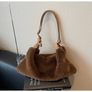 Gros plan d'un sac à main en fausse fourrure marron avec nœud sur la bandoulière en cuir