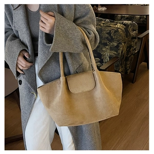 Detalle del bolso tote de ante camel llevado con un abrigo de lana gris en un café