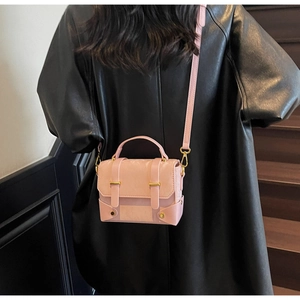 Roze getextureerde leren crossbodytas met gouden gespen gedragen door een model