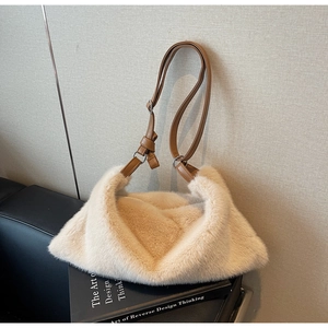 Détail d'un sac bandoulière en peluche crème avec une sangle en similicuir marron