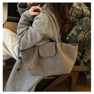 Detalle del bolso tote de ante taupe mostrando la textura suave y el cierre de solapa grande