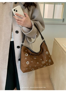 Brown suede hobo bag featuring silver metal eyelets and a vintage minimalist retro vibe