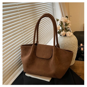 Primer plano del bolso tote de ante marrón mostrando su textura mate y las costuras reforzadas