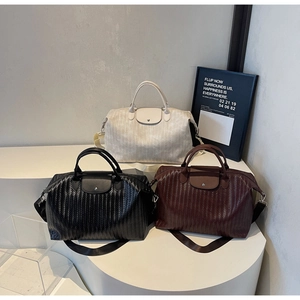 Trois sacs de voyage tissés en beige, noir et brun rouge sur des supports blancs élégants