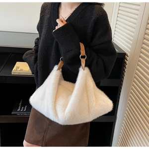 Sac fourre-tout blanc en peluche douce avec poignées en cuir marron porté par un mannequin