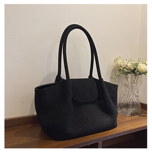 Detalle del bolso tote de ante negro con asas dobles y cierre de solapa frontal
